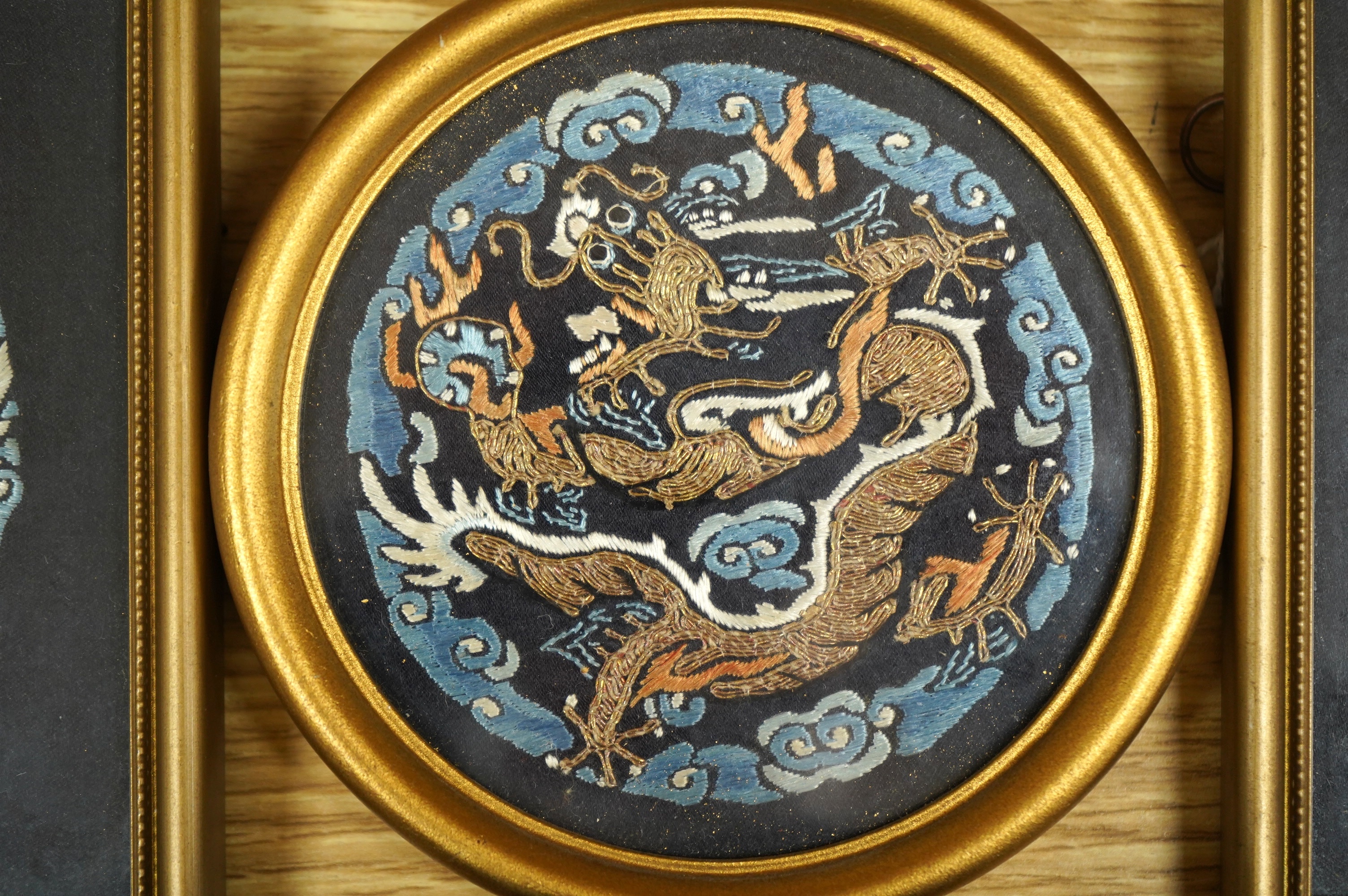 Three Chinese early 20th century embroidered roundels of five claw dragons, embroidered in gold thread and blue silk thread possibly symbolic motifs cut from a robe, embroidery 9cm diameter. Condition - embroidery good,